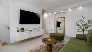 A modern living room with a flat-screen TV, white cabinetry, a green sofa, and a small round coffee table. - Casa Riccardo Premium Holday Home (Funtana)