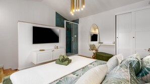 A modern bedroom with a large bed, a TV mounted on the wall, a walk-in closet, and a bathroom with a glass shower. - Casa Riccardo Premium Holday Home (Funtana)