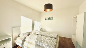 A bedroom with a bed, bedside tables, a wardrobe, and a hanging light fixture.
