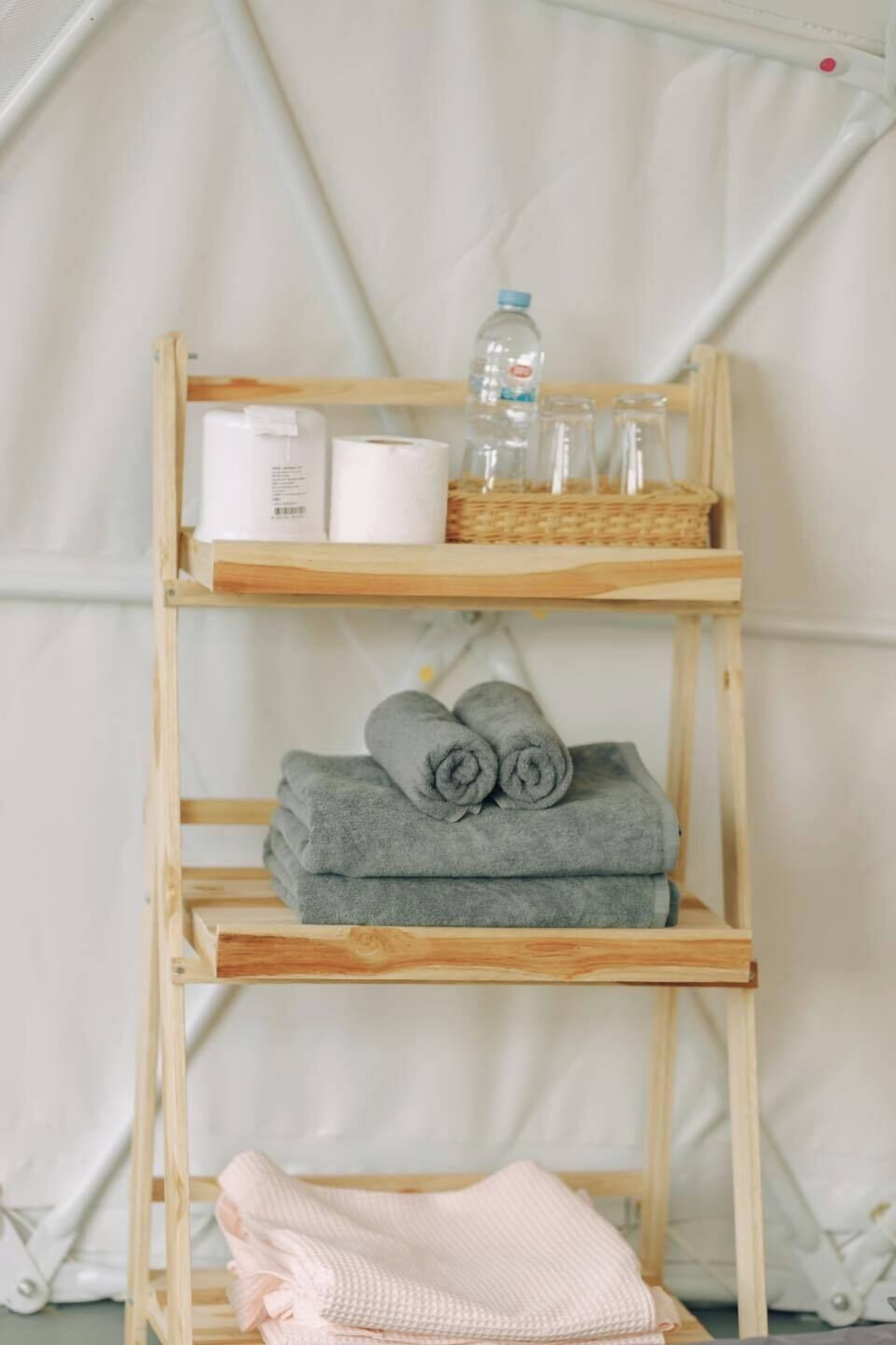 A wooden shelf with towels, a water bottle, and toiletry items.