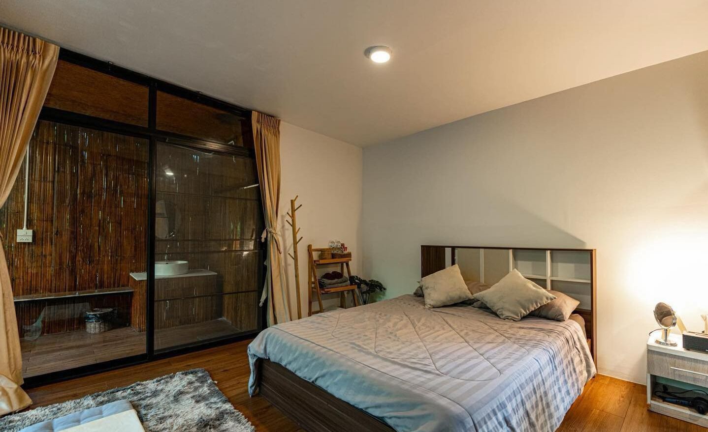 Un dormitorio con un amplio ventanal corredera, una cama con cabecera y una mesita de noche.