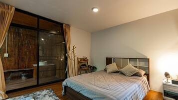 A bedroom with a large sliding glass door, a bed with a headboard, and a bedside table.