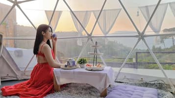 A tented area with a table set for tea, a cake, and snacks.