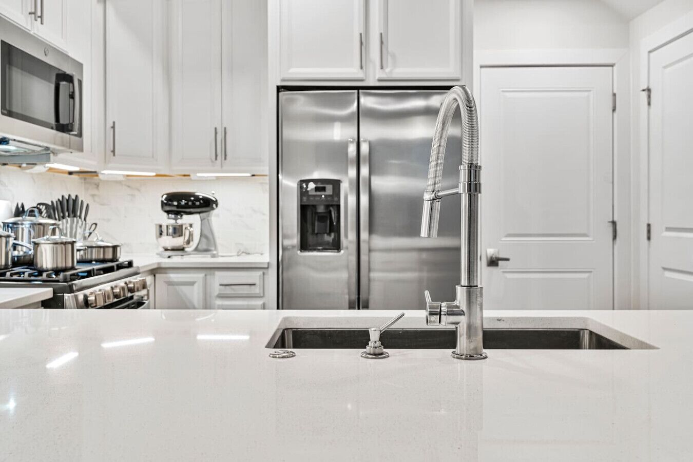 A modern kitchen with stainless steel appliances, a double sink, and white cabinetry.