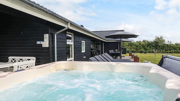 A hot tub in front of a house with a patio area and a covered table. - 5 Star Holiday Home in Hadsund (Hadsund)