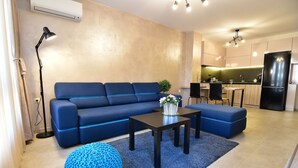 Una sala de estar moderna con un sofá azul, una mesa de centro y un taburete tejido en tono azul.