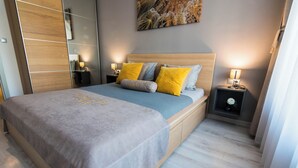 Un dormitorio moderno con una cama grande, mesitas de noche, un espejo y una obra de arte en la pared.