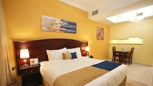 A hotel room with a large bed, two bedside tables with lamps, a desk with chairs, and artwork on the walls. - Imperiaa by HOC Globe (Dubai)