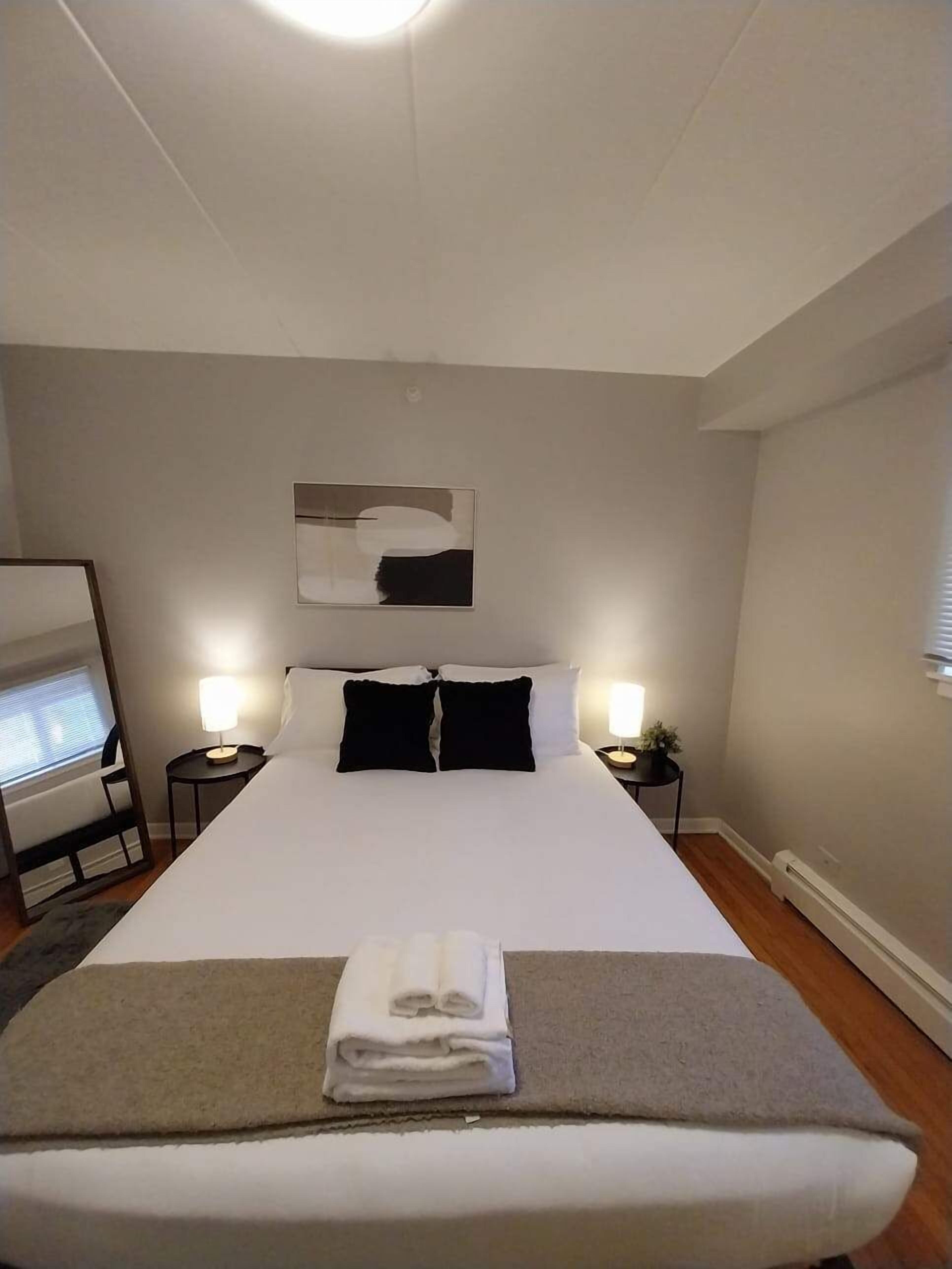 A hotel room with a large bed, two bedside lamps, a flat-screen TV, and a painting on the wall.