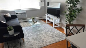 Una sala moderna con sofá, mesa de centro, televisor y una planta.