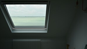 A room with a skylight, a radiator, a bedside table with a lamp, and a bed.