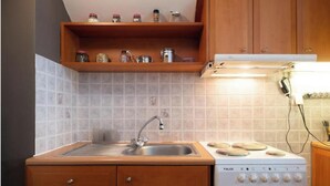 A compact kitchen with a sink, stove, and wooden cabinets. - Levanda Syros with Free Parking (Ermoupoli)