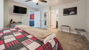 A bedroom with a bed, a ceiling fan, a TV, and a painting on the wall. - Welcome to Mountain Getaway in this cozy 4 bed 3 bath home. (Idaho Falls)