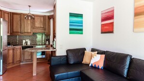 Una cucina moderna con mobili in legno, un divano in pelle nera e arte astratta alle pareti.