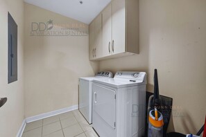 Une buanderie équipée d’un lave-linge, d’un sèche-linge et d’un aspirateur.