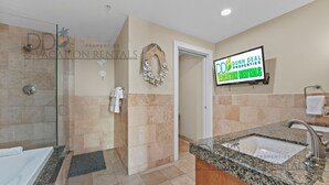 Une salle de bain avec une douche à parois de verre, un lavabo sur un plan de travail en granit et un porte-serviettes.