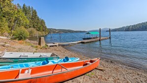Une scène au bord du lac, avec une barque à rames et un canoë amarrés à un quai en bois.