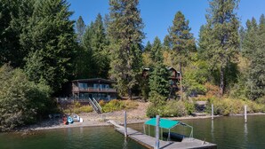 Une cabane au bord d’un lac, avec un quai et une zone abritée.