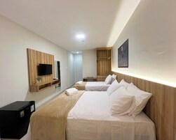 Habitación de hotel con dos camas, un televisor instalado en un panel de madera, un escritorio y un armario.