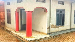 A building with a tiled entrance area, red pillars, and a door with a window. - Immaculate 10-bed Lodge in Kigali (Kigali)