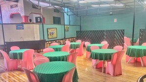 A dining area with round tables covered in green tablecloths, pink chairs, and a tiled floor. - Immaculate 10-bed Lodge in Kigali (Kigali)
