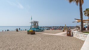 Een strand met een redershutje, parasols en ligbedden.