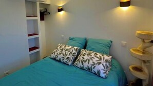 A bedroom with a bed, a built-in shelf unit, and a cat tree. - Apartment for rent - Cap d'Agde, plage Richelieu Sea view - Quiet - Comfort - (CAP D'AGDE)
