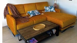 A living room with a sectional sofa, a coffee table, and a decorative plant. - Apartment for rent - Cap d'Agde, plage Richelieu Sea view - Quiet - Comfort - (CAP D'AGDE)