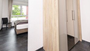Quarto moderno com cama, poltrona, guarda-roupa e janela.