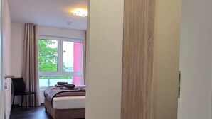 Quarto de hotel com uma cama, uma cadeira, uma janela com vista e um painel de madeira.