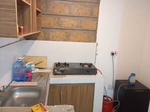 Eine kleine Küche mit einem Gasherd, einer Spüle und einer Arbeitsplatte.