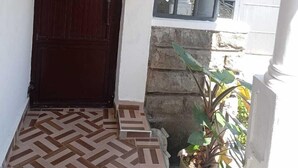 Una entrada frontal con una puerta de madera oscura, una ventana con diseño de cuadrícula y una planta en maceta.