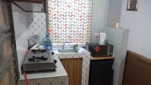 Cocina compacta con estufa a gas, lavamanos y un refrigerador pequeño.