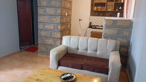 Una sala de estar con sofá, una mesa baja de madera y una zona de cocina al fondo.