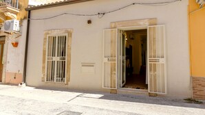 A building with two open windows, a door, and a small vent on the wall. - Casa Vico Ferruccio 24 (Noto (SR))