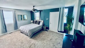 Ein Schlafzimmer mit Bett, Deckenventilator und Fernseher.