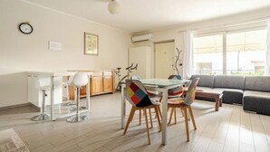 Ein modernes Wohnzimmer mit Essbereich, einer Couch und einer Küche im Hintergrund.