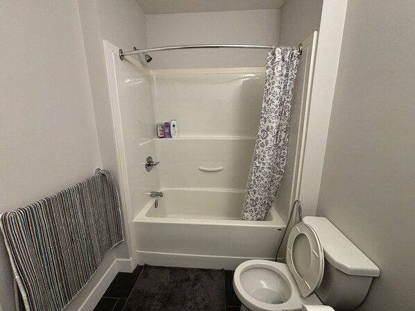 A bathroom with a bathtub, toilet, and a shower curtain.