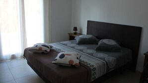 A bedroom with a bed, pillows, a nightstand, and a lamp.