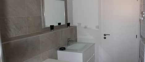 A bathroom with a large mirror, two sinks, and a toilet.