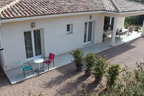 Una casa moderna con un porche cubierto, comedor y jardín.