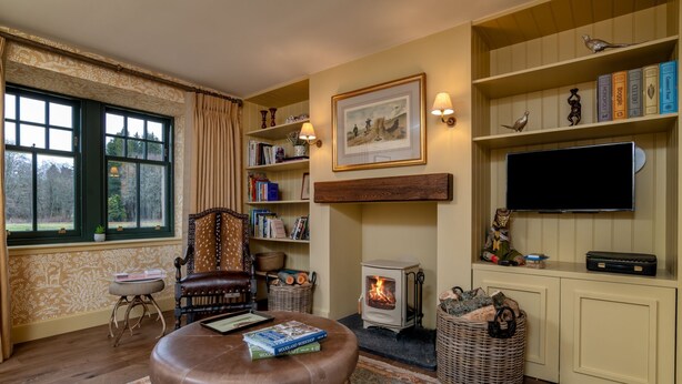 A cozy living room with a fireplace, bookshelves, a television, and a comfortable seating area. - Luxury rural escape in peaceful Aberdeenshire (Alford)