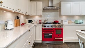 A kitchen with white cabinets, a red oven, a stainless steel range, and a microwave. - Greenstyle  - Countryside retreat with castle views (Kildrummy)