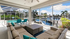 Un área de lounge al aire libre con sol, piscina, asientos y vista a un puerto deportivo.