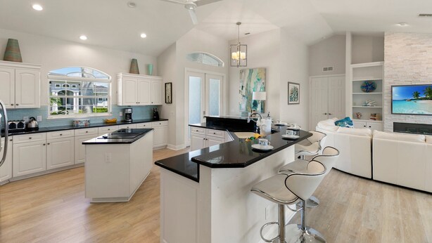 Una cocina amplia con armarios blancos, una isla central y un comedor con taburetes de bar.