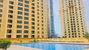 A modern high-rise building with a swimming pool in the foreground.