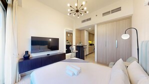 A modern hotel room with a large bed, a TV, a desk, and a kitchenette. - Peaceful Studio l Spacious & Bright l Meydan (Meydan)