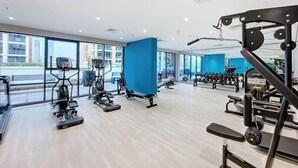 A modern gym with cardio machines, free weights, and a blue accent wall. - Peaceful Studio l Spacious & Bright l Meydan (Meydan)