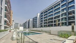 A modern building with a rooftop pool, glass railings, and a clear sky. - Peaceful Studio l Spacious & Bright l Meydan (Meydan)
