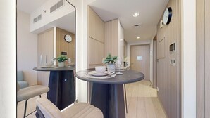 A modern hotel corridor with two round tables, each with a potted plant and a wine glass. - Peaceful Studio l Spacious & Bright l Meydan (Meydan)